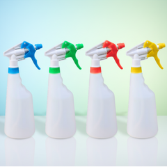 Four white spray bottles with colorful nozzles on a light background