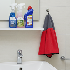 Bathroom with cleaning supplies on a shelf, a sink, and a red and gray towel hanging.